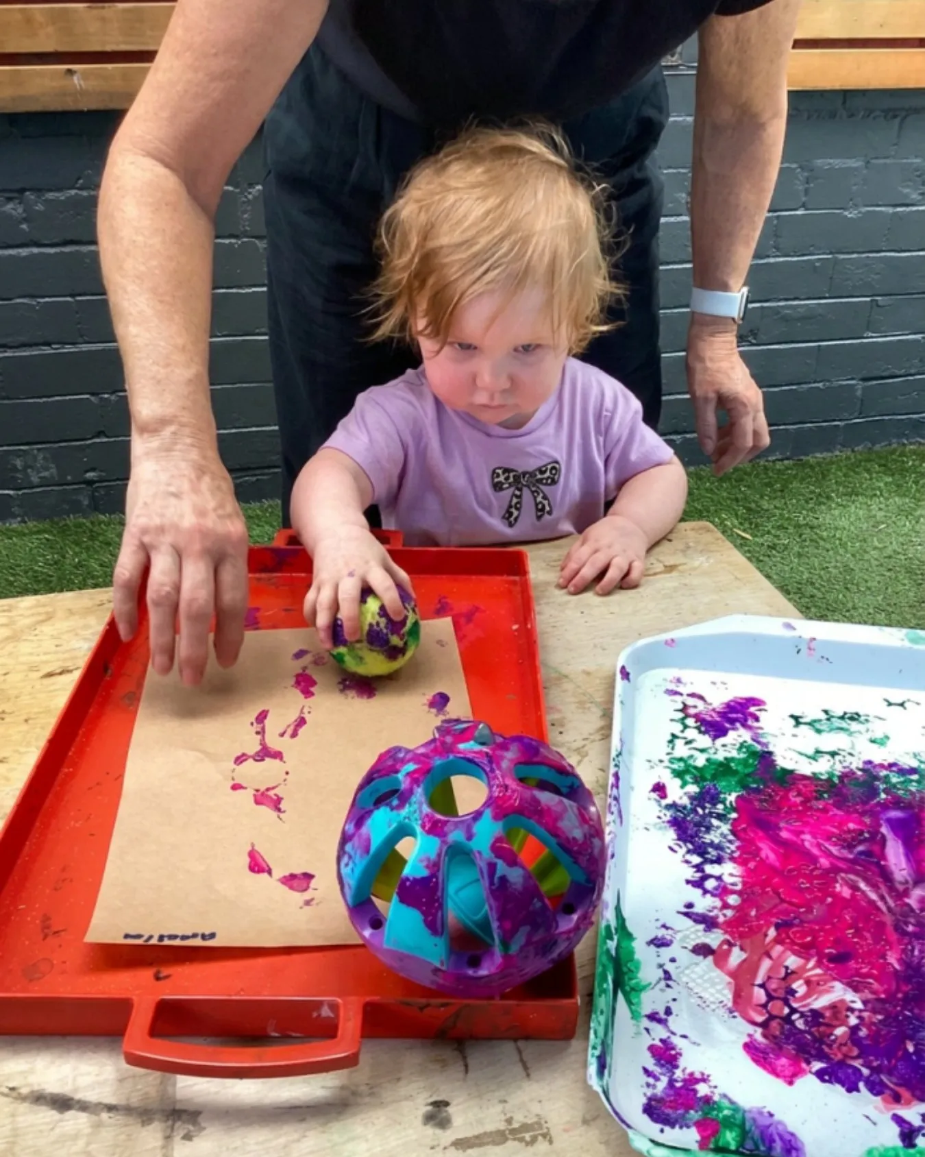 A toddler exploring messy play and painting at Global Explorers